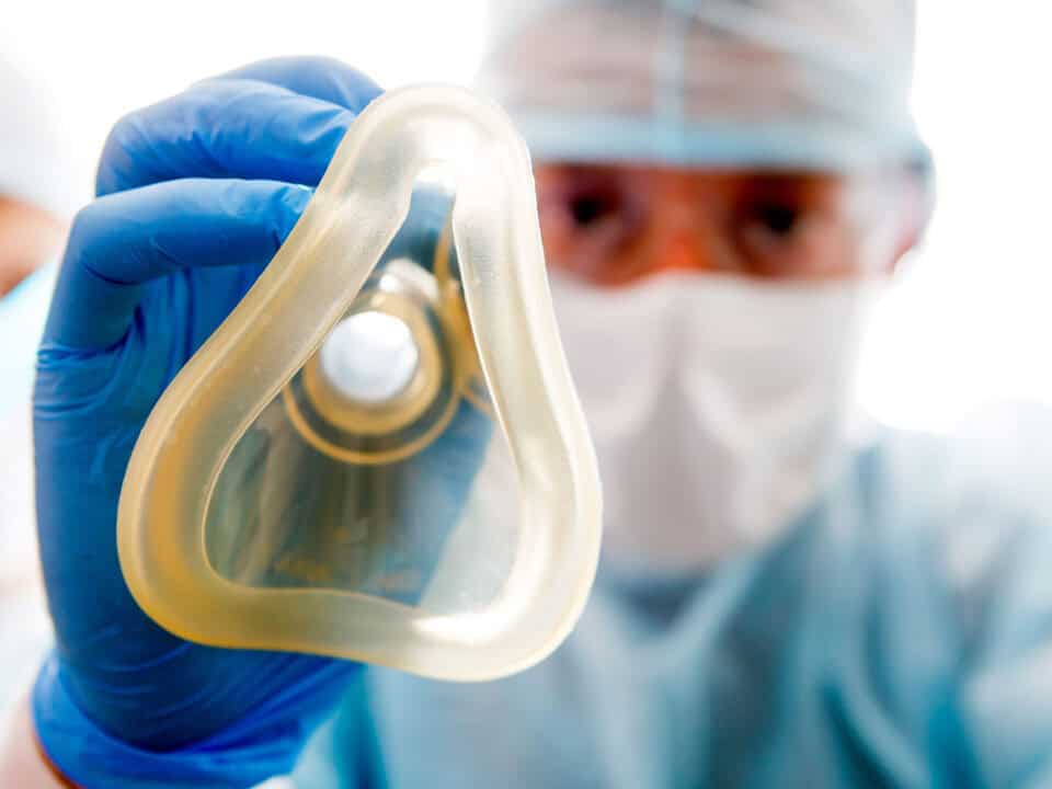 An anesthesiologist is holding a nitrous oxide mask