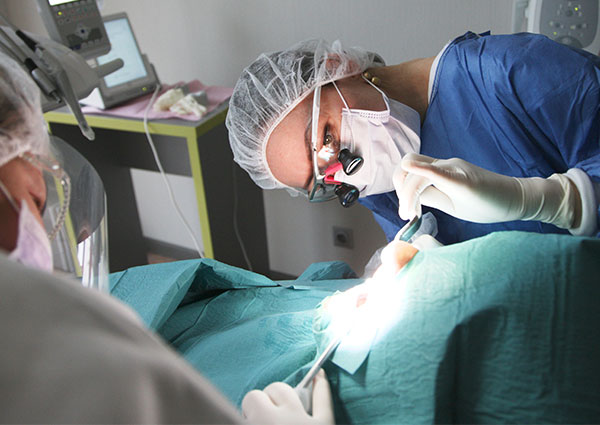 An oral surgeon performs surgery on a patient