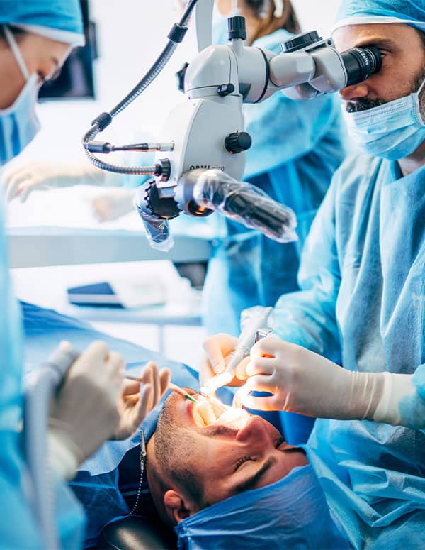 An oral surgeon performs surgery on a patient